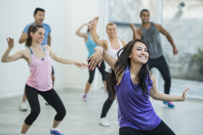 A multi-ethnic group of adults are indoors dancing